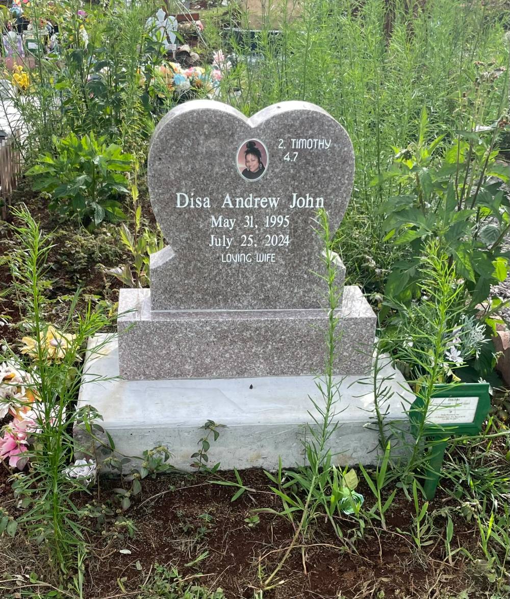 Heart-shaped gray granite headstone with a portrait, surrounded by flowers
