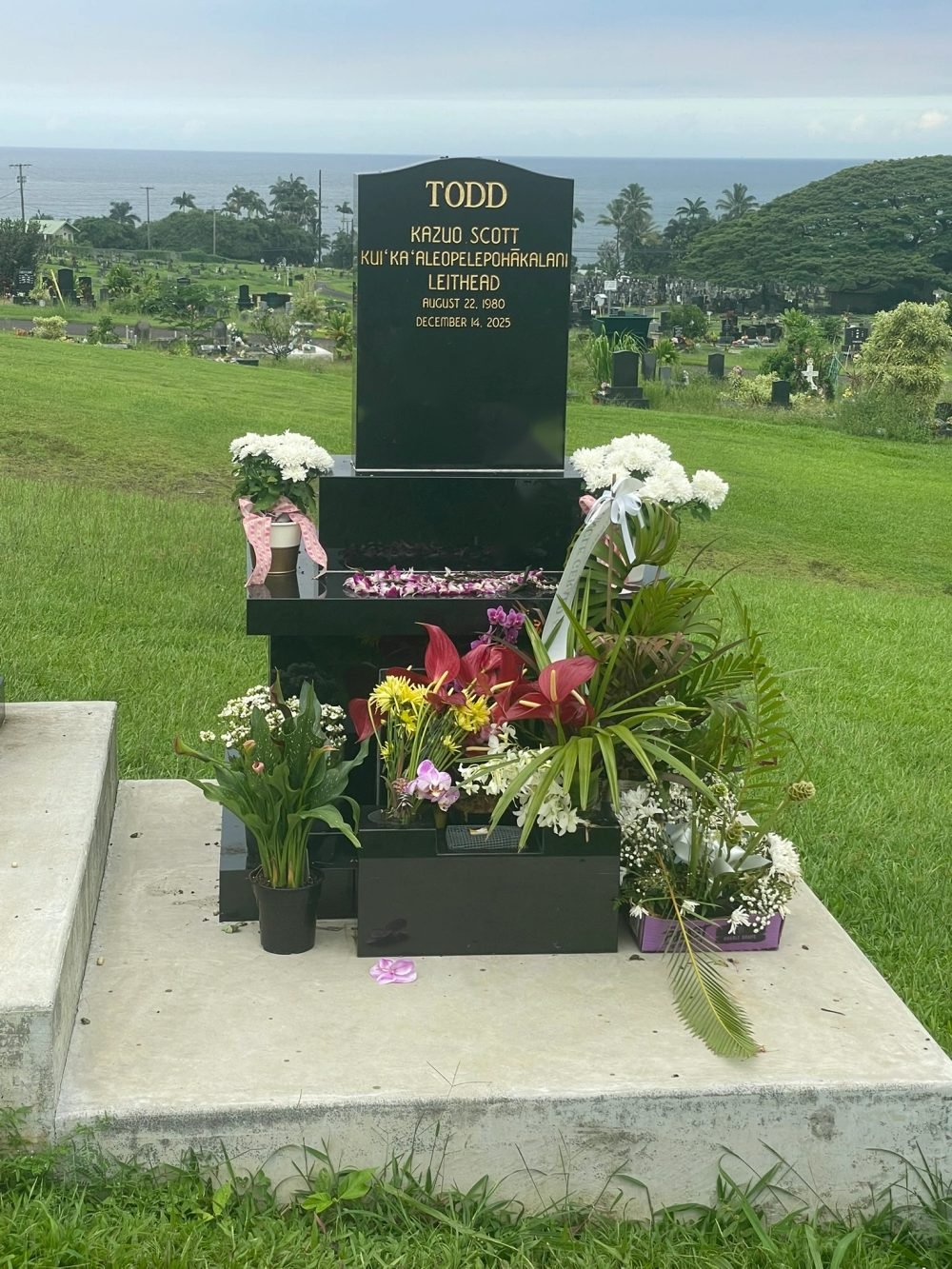 Haka House with floral tributes, overlooking the ocean